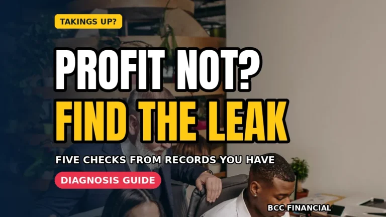 Owner working through sales up profit down small business checks with invoices and a calculator at a shop desk