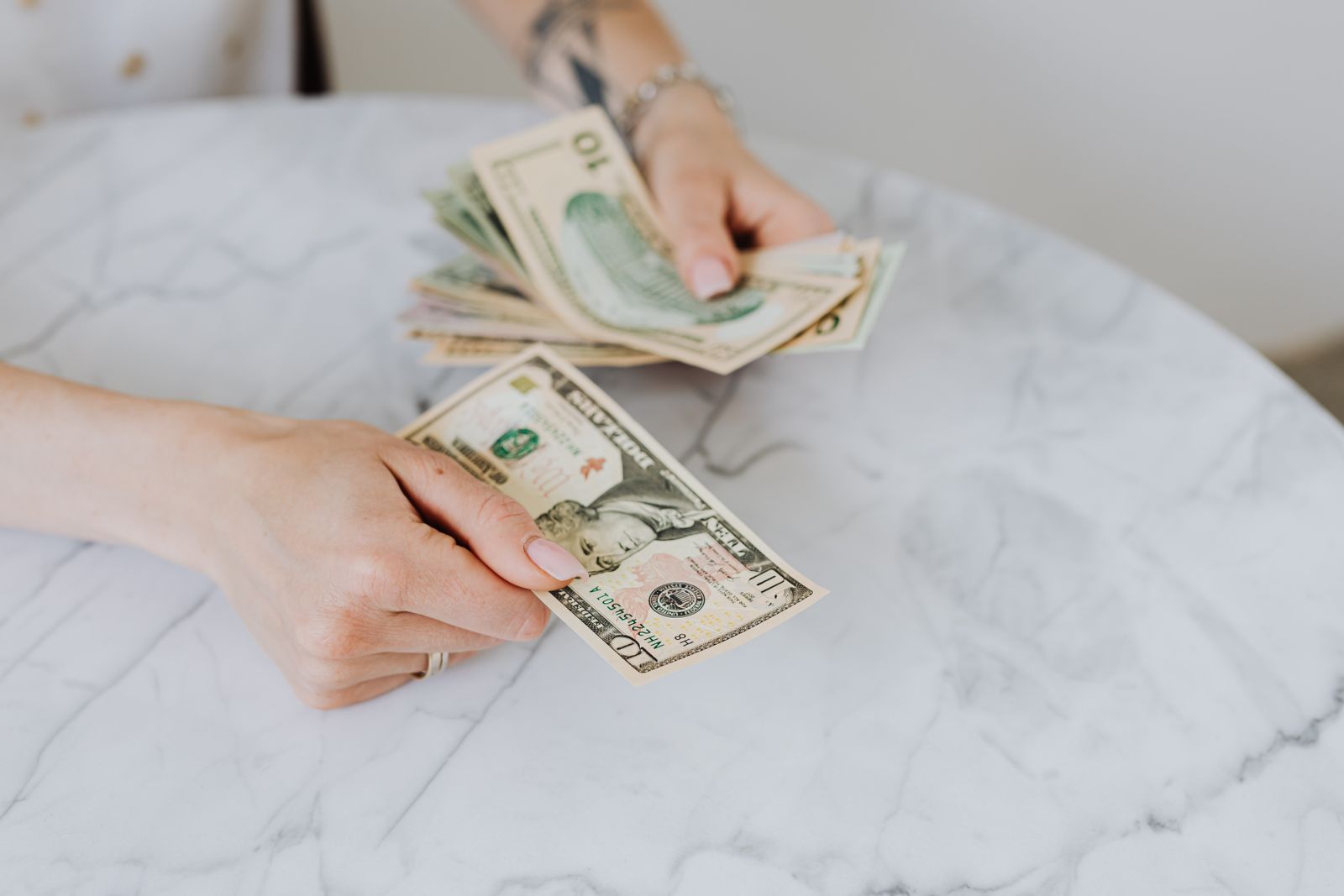 Hands counting US dollar bills on a table during a cash count
