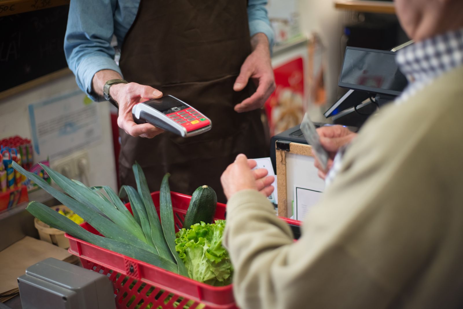 A customer paying by card at a grocery store checkout counter