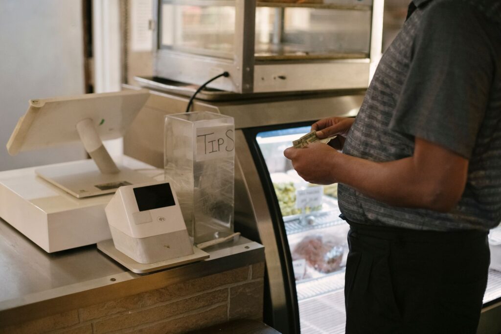 A customer making a cash payment at a store counter with a digital register
