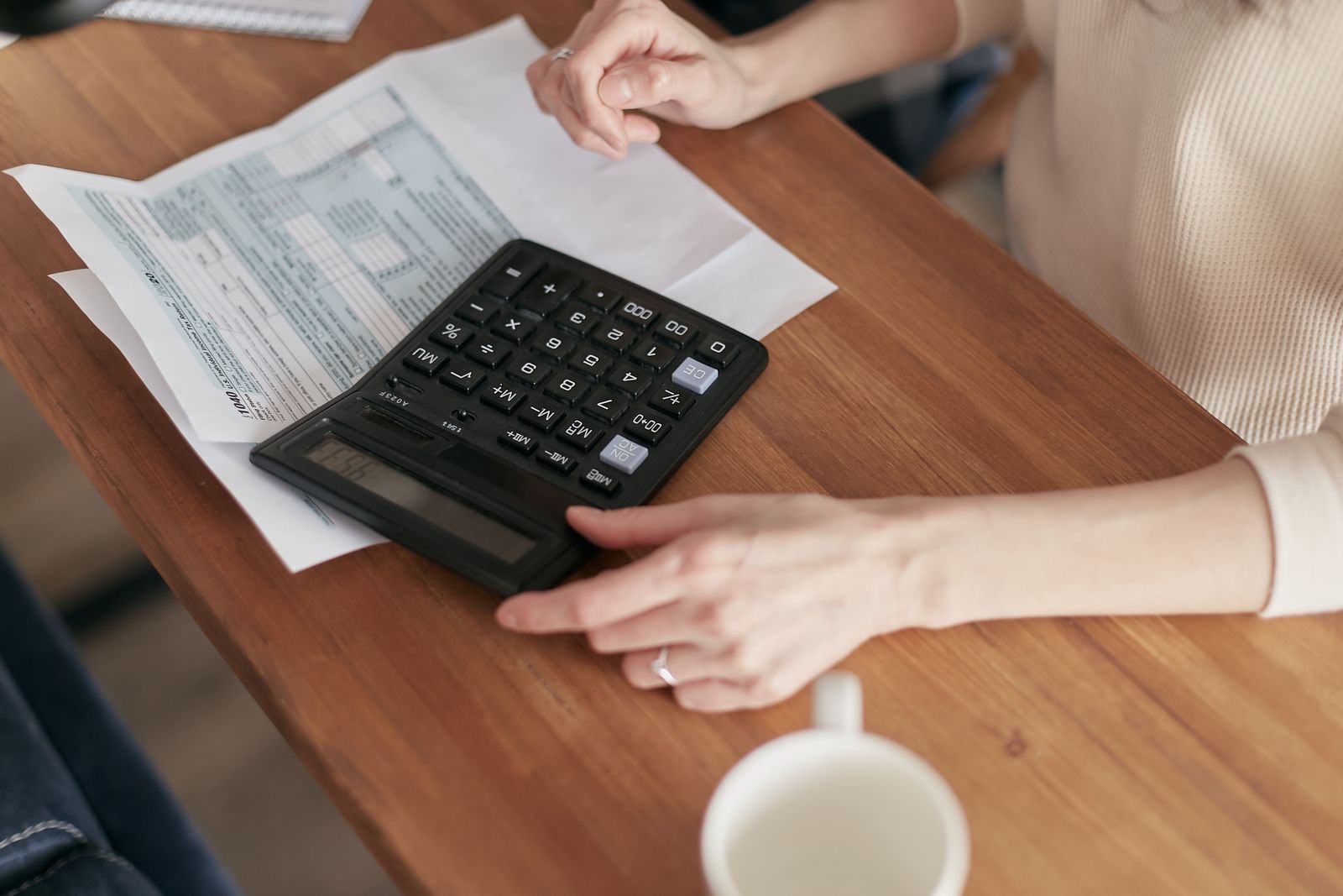 Hands checking figures with a calculator and paperwork at a desk