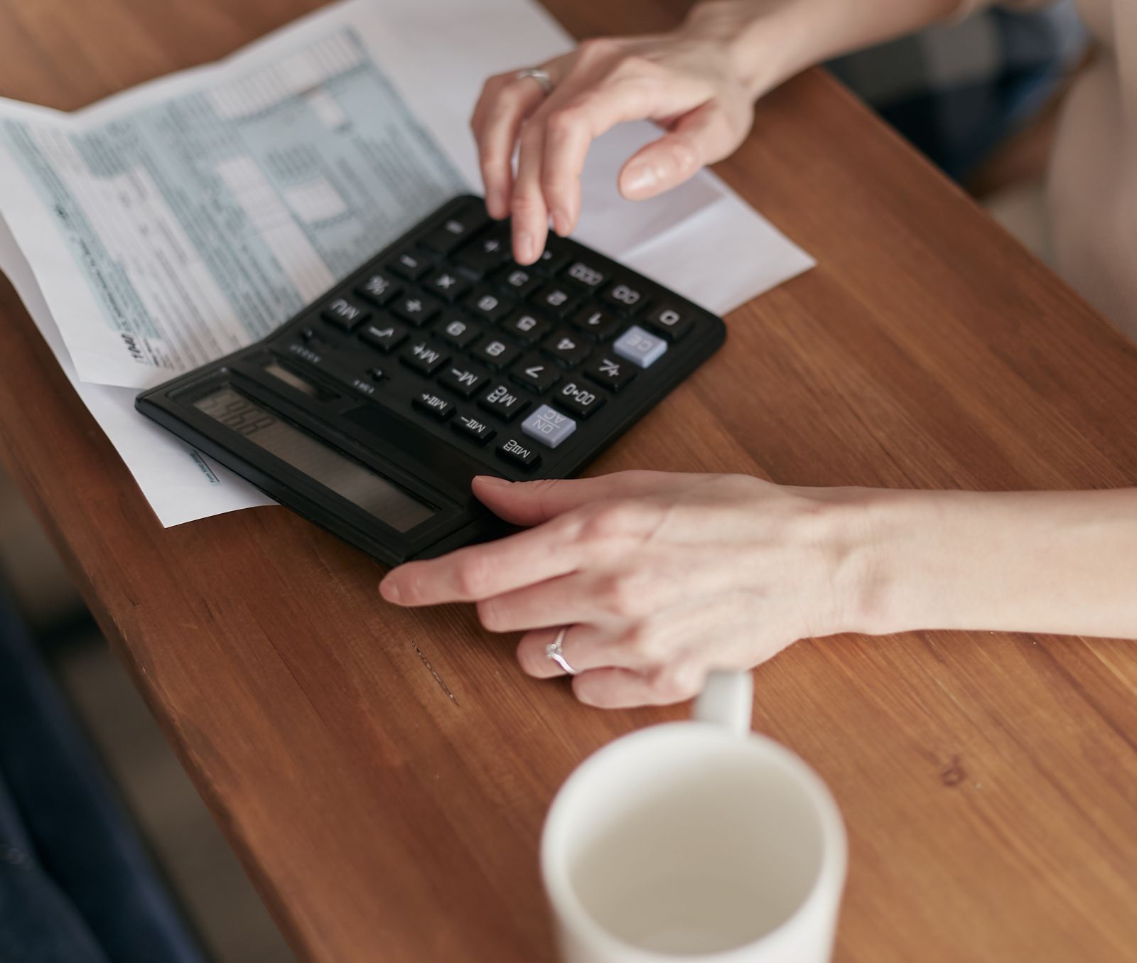 A business owner reviewing bills with a calculator as cash runs tight