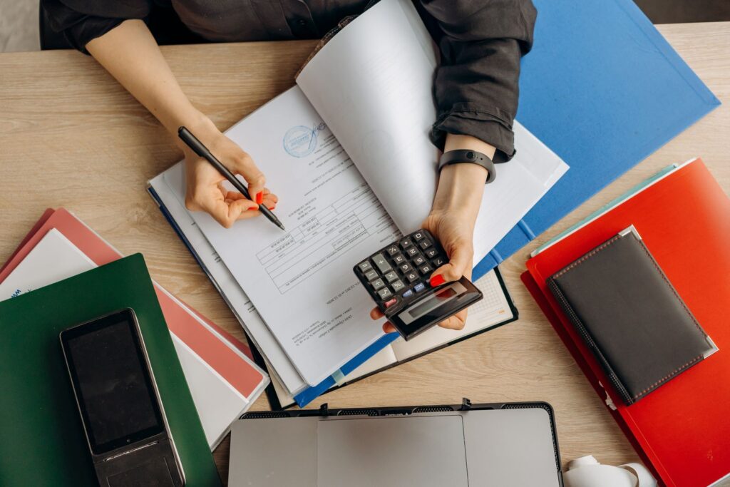 An accountant analysing financial documents with a calculator on a desk