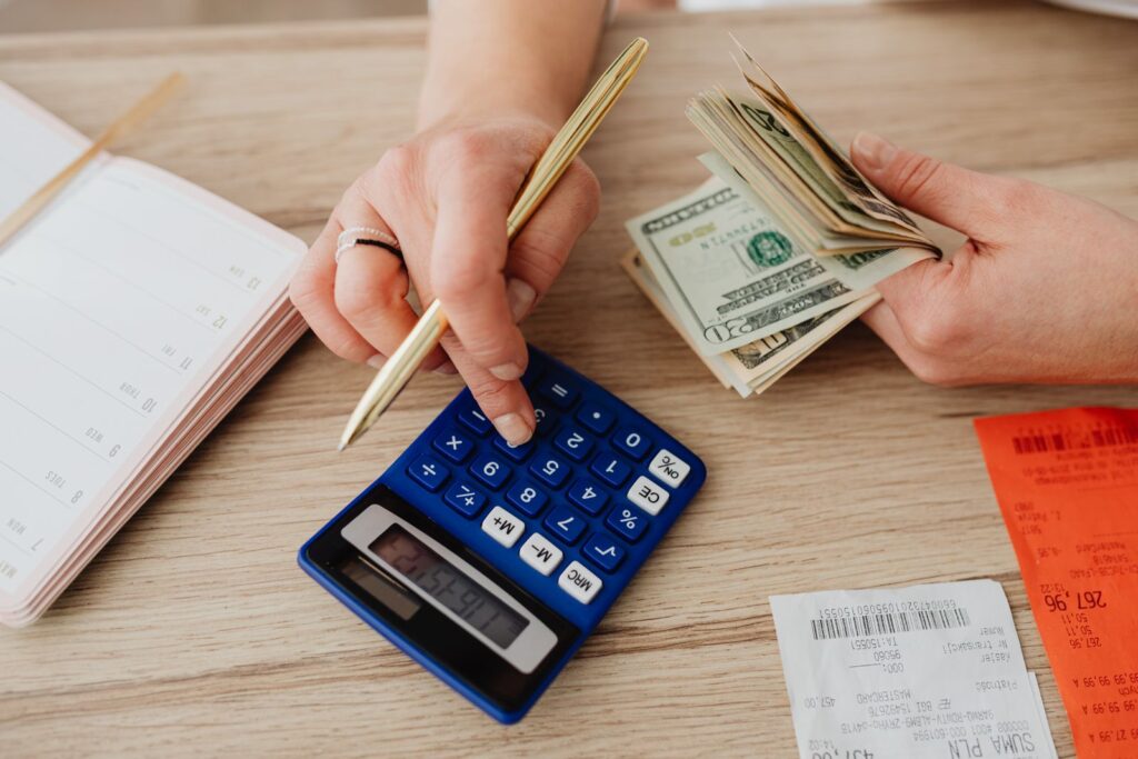 Hands counting cash with a calculator while working through a budget