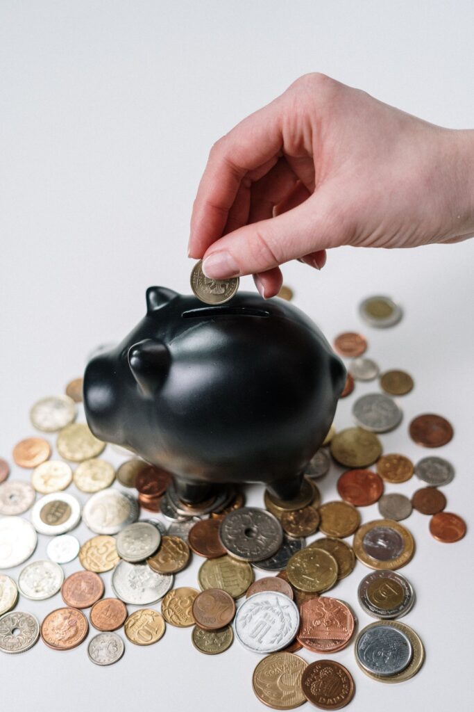 A hand adding a coin to a piggy bank to build up savings